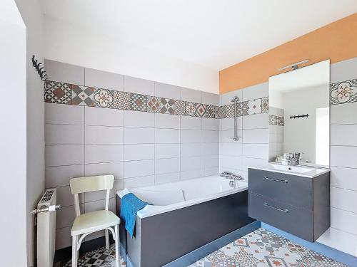 a bathroom with a tub and a sink and a chair at La Mainerie in Jobourg