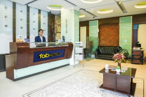 a man standing at a reception desk in a lobby at FabHotel Royal Residency II - Nr Lakdikapul Metro Station in Hyderabad