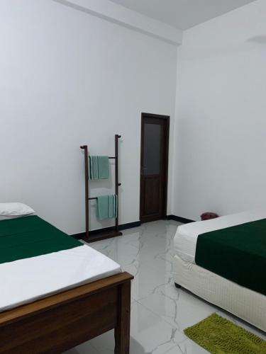 a bedroom with two beds and a door with towels at Wilpattu Nuga Lodge in Pahala Maragahawewa