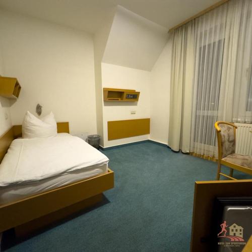 a hotel room with a bed and a chair at Hotel zum Sportforum in Blankenburg