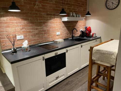 a kitchen with white cabinets and a brick wall at Maison MoDì in Taranto