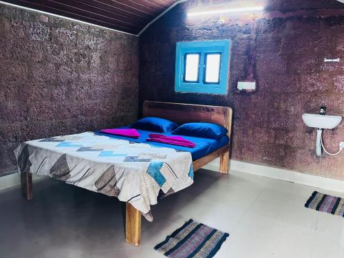 - une chambre avec un lit doté d'oreillers bleus et d'un lavabo dans l'établissement Sukhi Beach Cottage, à Gokarna
