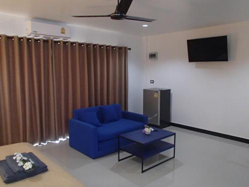 a living room with a blue chair and a flat screen tv at Coconoi Residence in Nai Harn Beach
