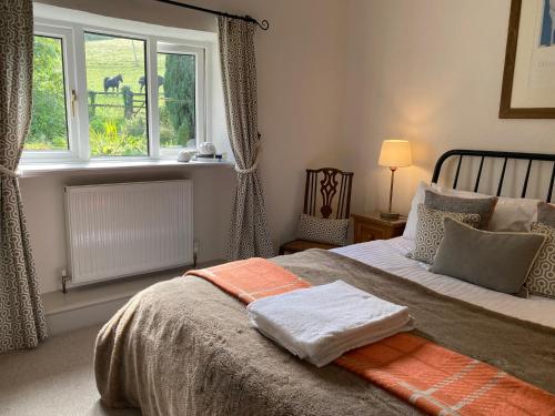 ein Schlafzimmer mit einem großen Bett mit Fenster in der Unterkunft Pardlestone Farm Cottages in Kilve