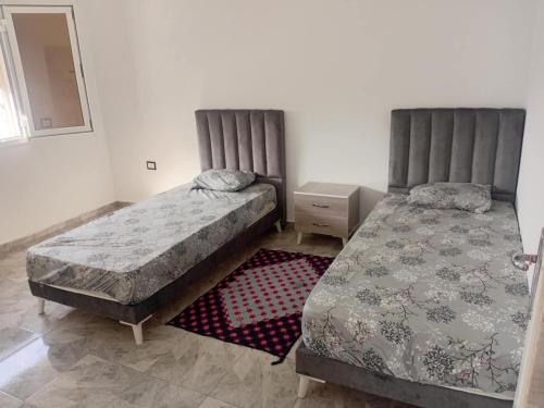 two beds sitting next to each other in a bedroom at résidence Ferjani hechmi in Rafrāf