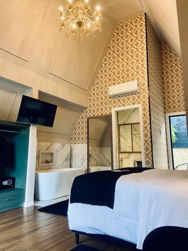 a bedroom with a bed and a tub and a chandelier at Hotel Villa Verde - by Easy Hotéis in São Bento do Sul