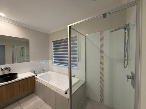 a bathroom with a shower and a sink and a tub at Pet Friendly &Home away From Home & Resort Facility in Rochedale