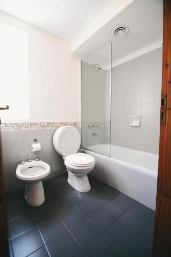 a bathroom with a toilet and a sink and a tub at Hosteria CuyenCO in Villa La Angostura