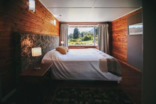 a bedroom with a large bed and a window at Hosteria CuyenCO in Villa La Angostura