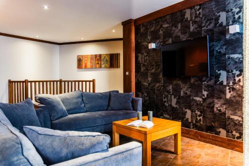 a living room with two blue couches and a tv at Résidence Montana Caron by Village Montana in Val Thorens