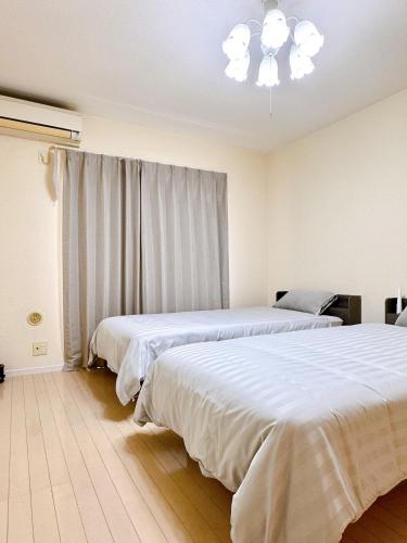 a bedroom with two beds and a chandelier at セレーナ南福岡 in Fukuoka