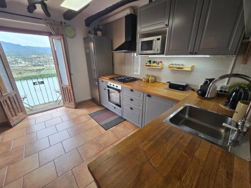 eine Küche mit Küchengeräten aus Edelstahl und einem großen Fenster in der Unterkunft Casa Rural Griso in Riba-roja d'Ebre