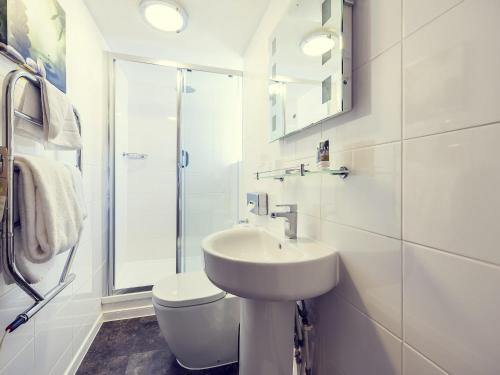 a white bathroom with a sink and a toilet at Mercure Nottingham City Centre Hotel in Nottingham