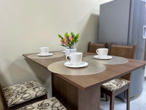 a wooden table with cups and saucers on it at Espaçosa casa com WI-FI Perto do Aroporto - Conforto e Praticidade in Joinville