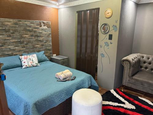 ein Schlafzimmer mit einem blauen Bett und einem Stuhl in der Unterkunft Lakeboutiquehotel empire new in Thohoyandou