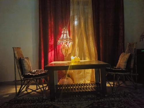 a table with a lamp in a room with chairs at Peace Abode Vista 1BHK in Dibrugarh