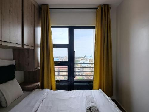 een slaapkamer met een bed en een raam met gele gordijnen bij Executive Studio Kinoo in Rungiri