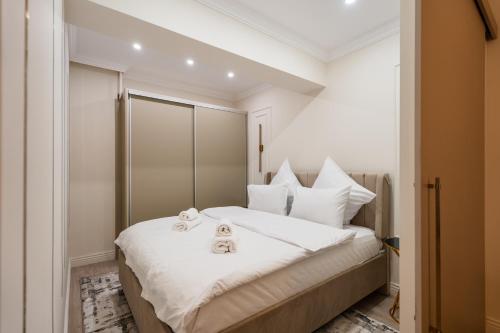 une chambre avec un lit blanc avec deux serviettes dessus dans l'établissement Ivory Garden Studio by Blvd 51B7 - Premium Voluntari Stay, à Bucarest
