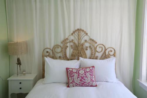 a white bed with a wooden headboard and a pink pillow at Bosch Huse Rosé - Zomer in Savannah