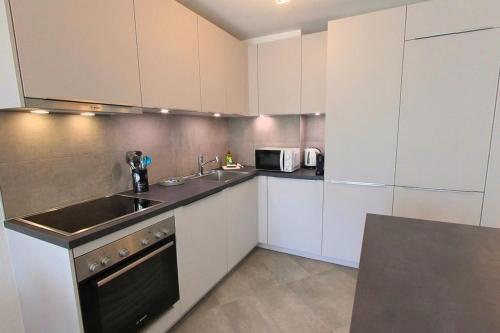 a kitchen with white cabinets and a sink at Luminous 2-Bed Apartment with Spacious Terrace RSC70-GF in Nyon