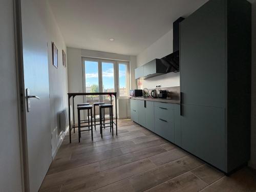 eine Küche mit einem Tisch und einigen Hockern in der Unterkunft Appartement Pop et coloré au coeur de Dunkerque in Dunkerque