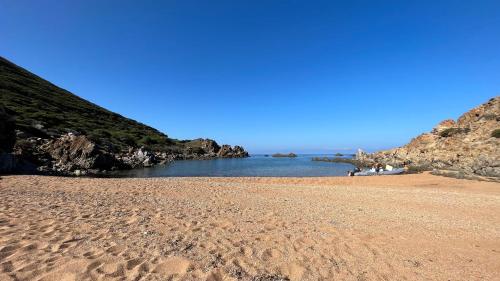 a sandy beach with rocks in the water at Isola Rossa Appartamenti Comfort plus in Isola Rossa