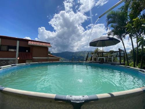 a large swimming pool with an umbrella in front of a building at Finca Panoramica in Barbosa