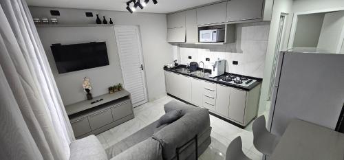 a living room with a couch and a kitchen at RG Kitnet01 in Curitiba