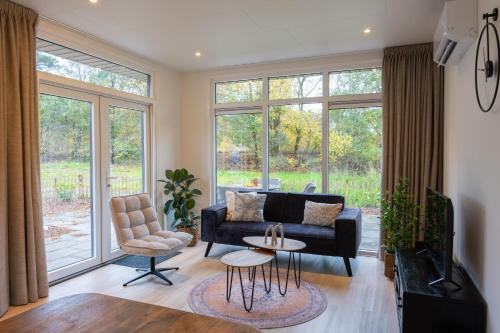 Una sala de estar con un sofá negro y un televisor. en Chalet Vlinder, en Haarle