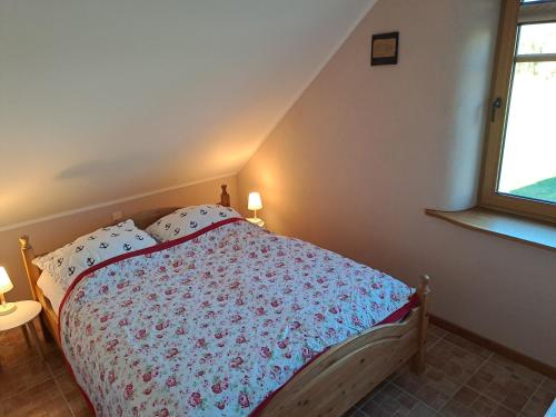 a bedroom with a bed with a floral bedspread and a window at Naturhof-Goldbeck in Klütz