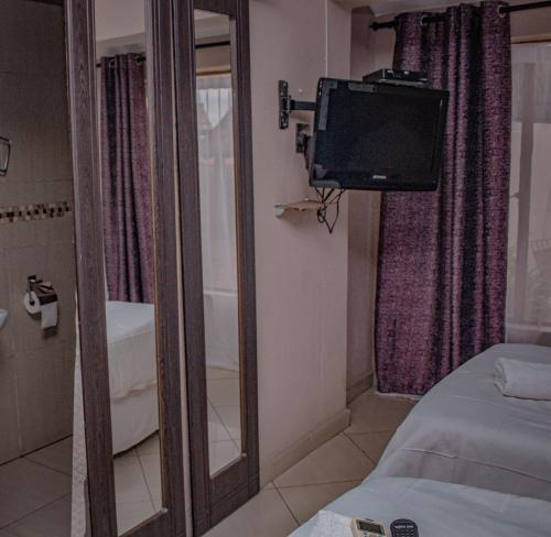 a mirror in a room with a tv and a bed at Nomanini Guesthouse in Nelspruit