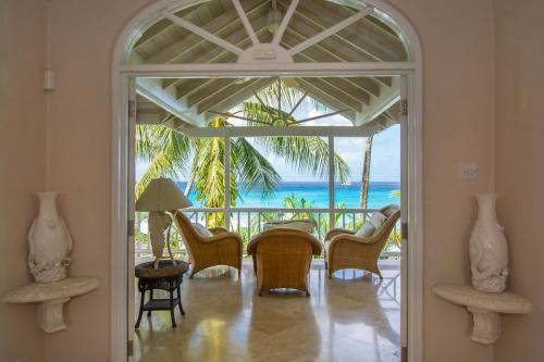a dining room with a table and chairs and the ocean at Ebbtide villa in Saint James