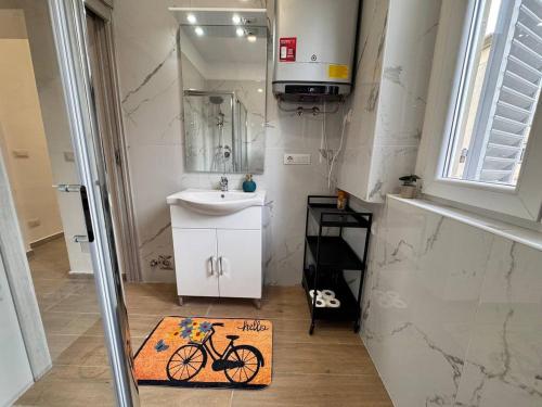 a bathroom with a sink and a bike rug on the floor at Cozy apartment near downtown in Turin