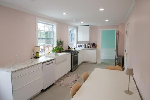 eine Küche mit weißen Schränken, einem Tisch und einem Tisch mit einem sidx sidx sidx in der Unterkunft Bosch Huis Rosé - Entire Property in Savannah