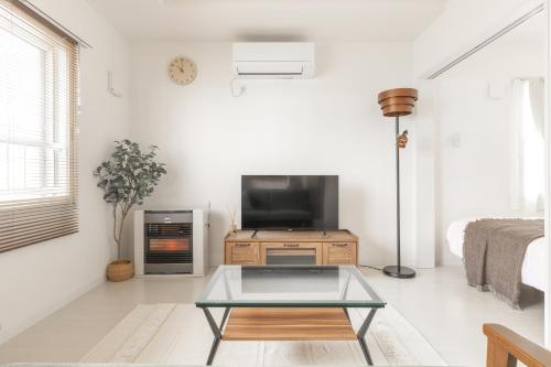 a living room with a tv and a coffee table at Cozy Stay Sapporo Maruyama Ibiza in Sapporo