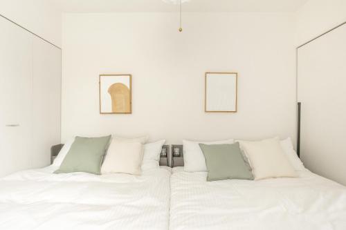 a white bedroom with two beds and two framed pictures at Cozy Stay Sapporo Maruyama Ibiza in Sapporo