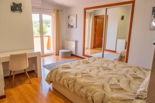 a bedroom with a large bed and a desk and a window at Verde Verdilhão Villa 