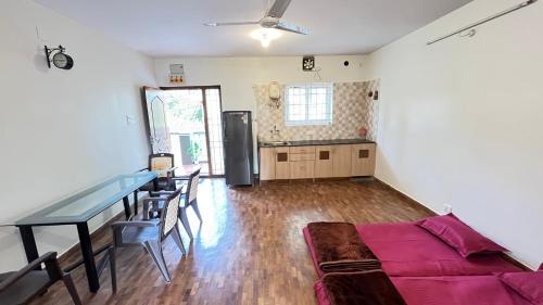 a living room with a table and a refrigerator at Vivens Villas in Ooty