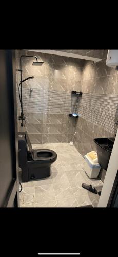 Un baño con un inodoro negro y un lavabo. en شاليه داله العماريه2 بالكامل لك وأجواء ممتعه, en Al ‘Ammārīyah