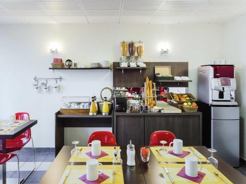 una cocina con 2 mesas y sillas rojas en Aparthotel Adagio Access Orléans, en Orléans