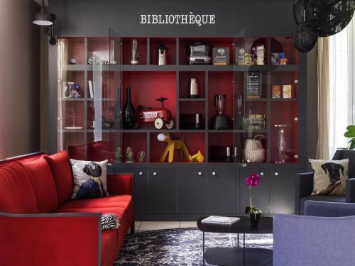 a living room with a red couch and some shelves at Aparthotel Adagio Access Nantes Viarme in Nantes