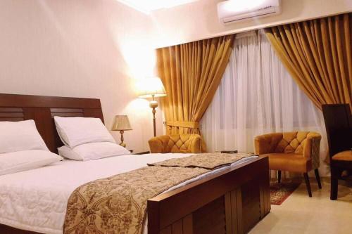 a hotel room with a bed and a chair at The Serenity Inn Family Hotel in Karachi