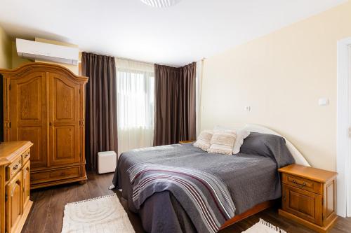 a bedroom with a bed and a wooden dresser at Вила "Роза" in Lakarevo