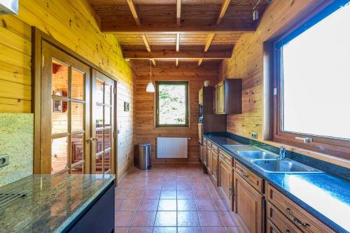 a large kitchen with wooden walls and a large window at Sous le Cielle d'Ardenne in La Roche-en-Ardenne