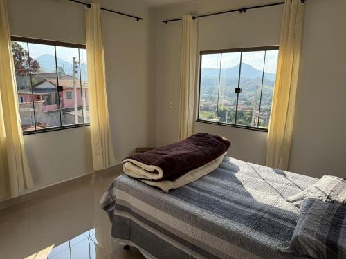 a bedroom with two windows and a bed with a blanket at Casa com visual deslumbrante in Carvalhos