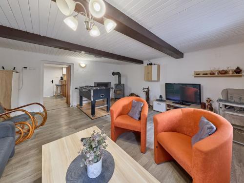 a living room with orange chairs and a flat screen tv at Holiday Home Leisure Lounge & Pool by Interhome in Kvasiny