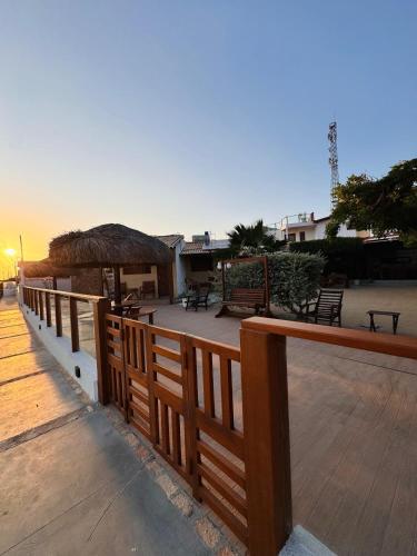 a wooden fence with a deck with tables and a hut at Pousada Rio Aratuá in Galinhos