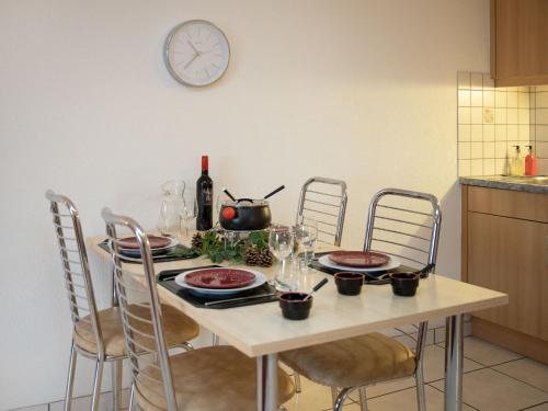 a table with plates and wine glasses and a clock on the wall at Apartment Réze 5 by Interhome in Ovronnaz