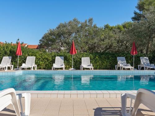 een zwembad met stoelen en parasols bij Apartment Luce by Interhome in Vir
