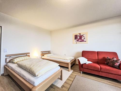 ein Schlafzimmer mit zwei Betten und einer roten Couch in der Unterkunft Apartment B715 by Interhome in Lahnstein